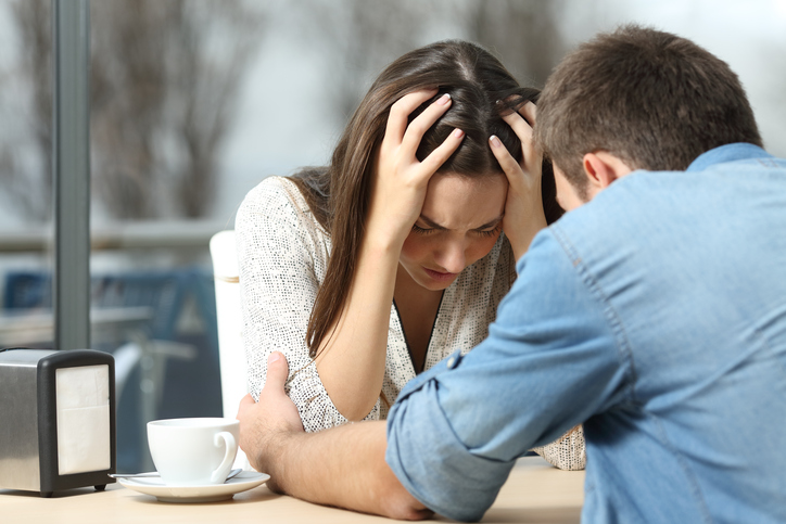 Male comforting to a sad depressed female who needs help in a coffee shop. Break up or best friend concept