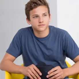 A young man sitting in a chair with a woman talking to him.