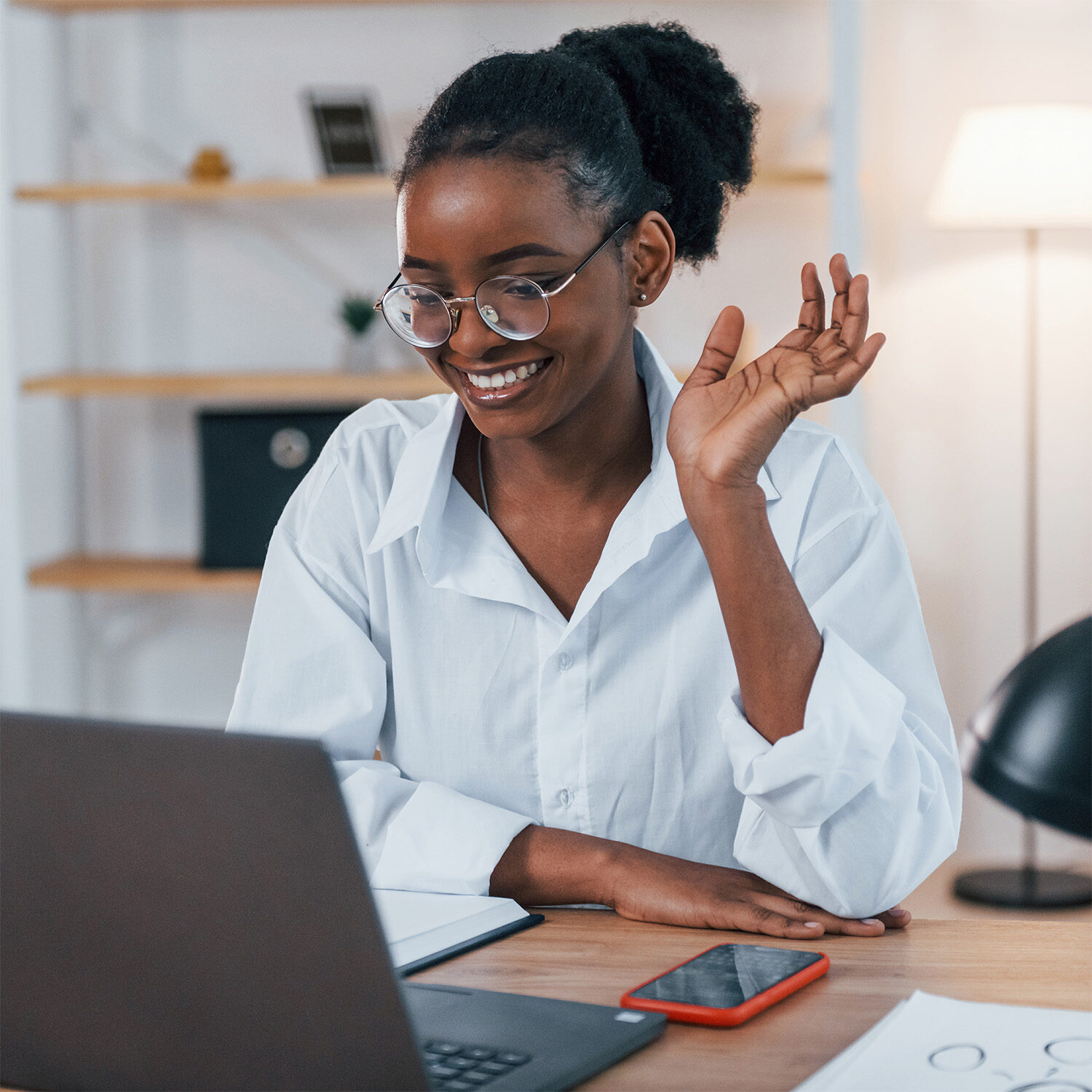 A young black woman sitting at a desk with a laptop.